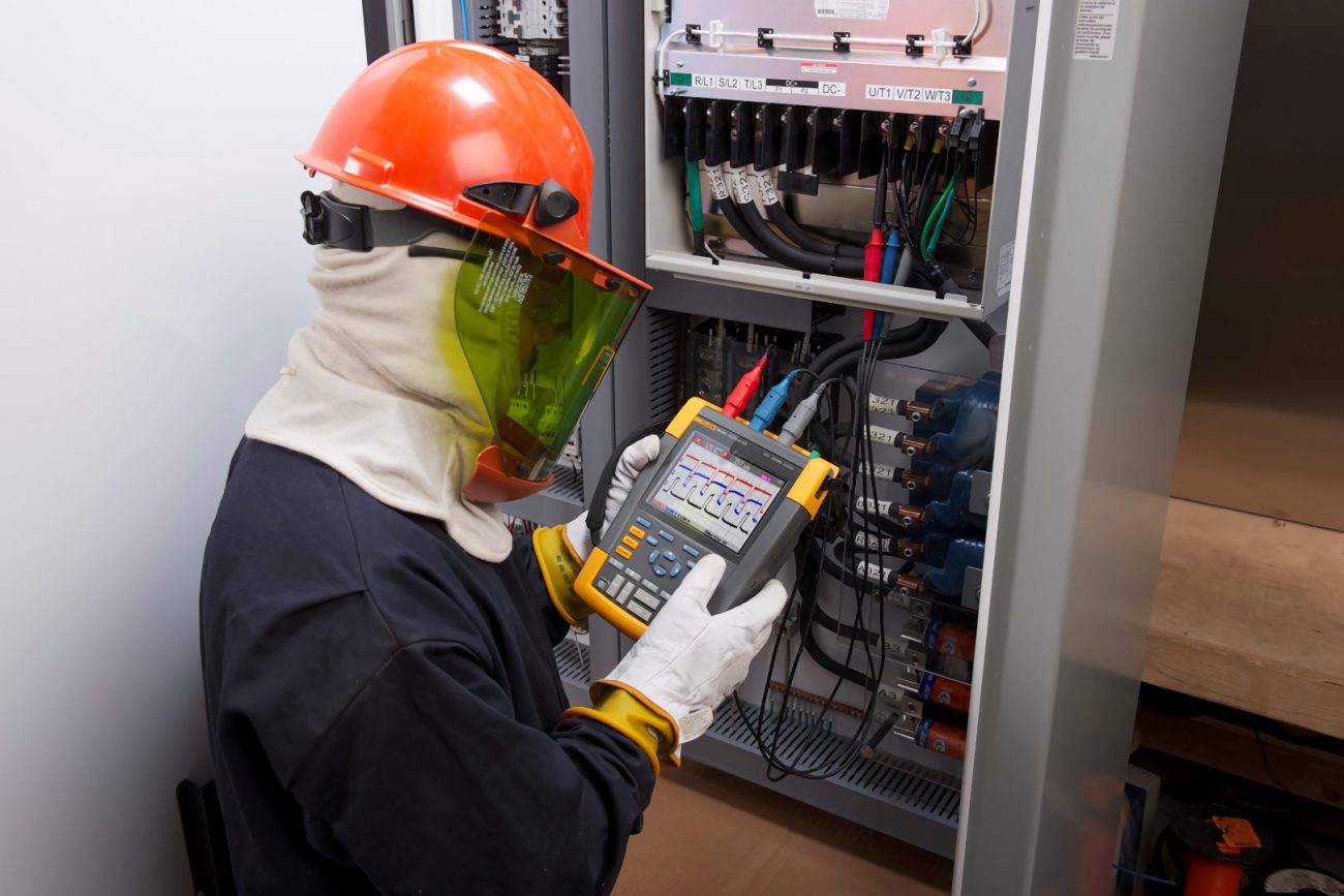 electrician using a power analyser on electrical switchboard