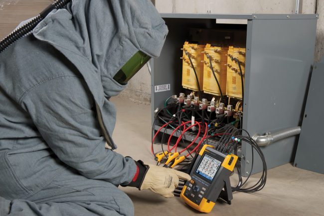 electrician wearing explosion suit measuring power on transformer
